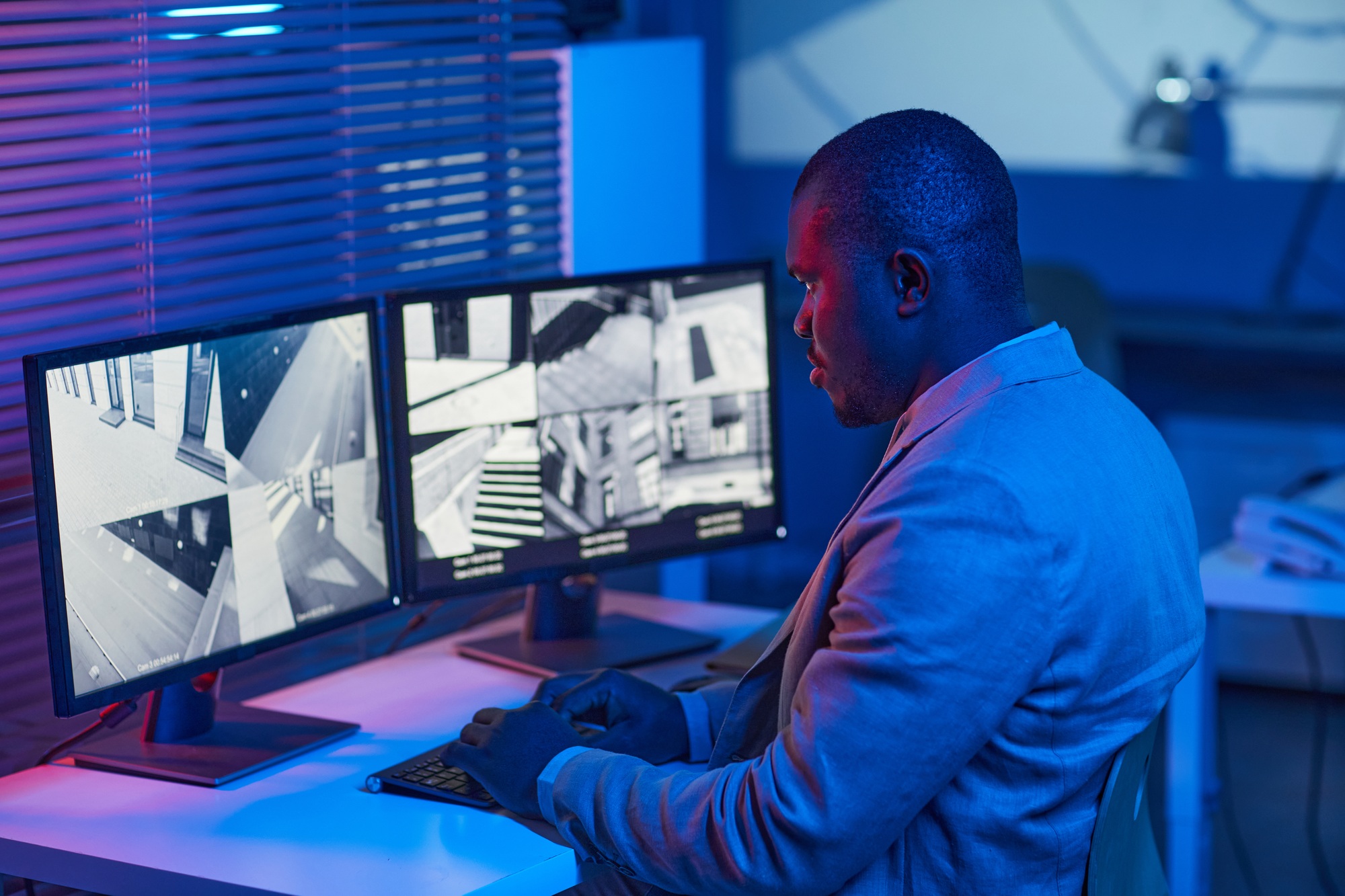 Black man looking at surveillance camera footage in security center office