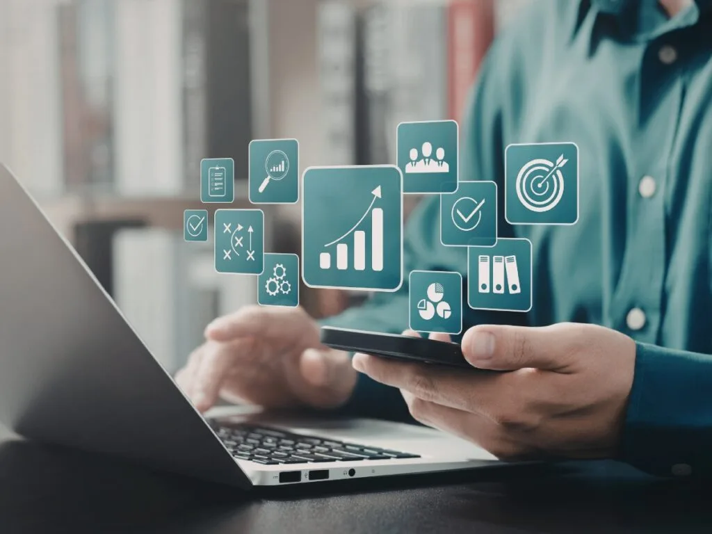 A person using a smartphone and laptop with business analytics, data visualization icons, and Digital Forensics Basics concepts digitally superimposed in front of them.